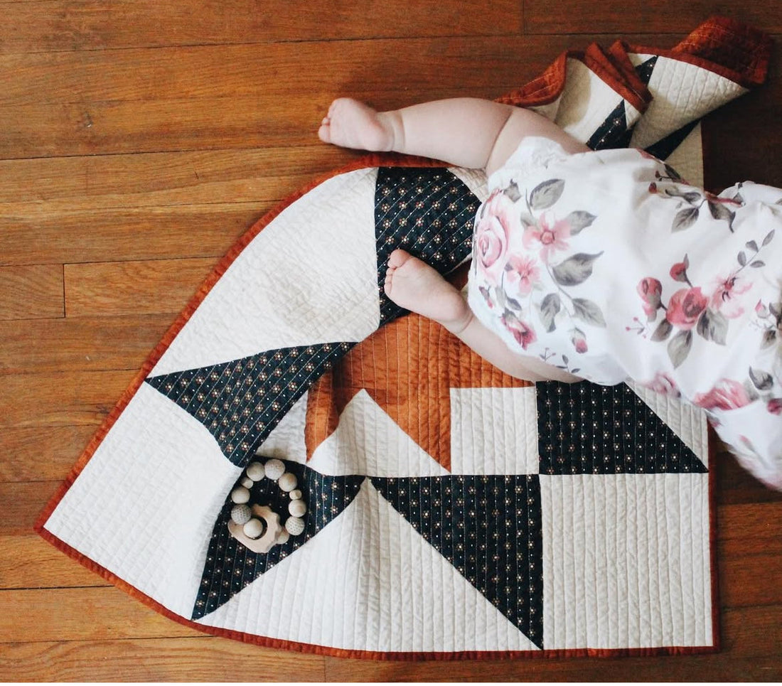 A baby crawling across a quilt on the floor